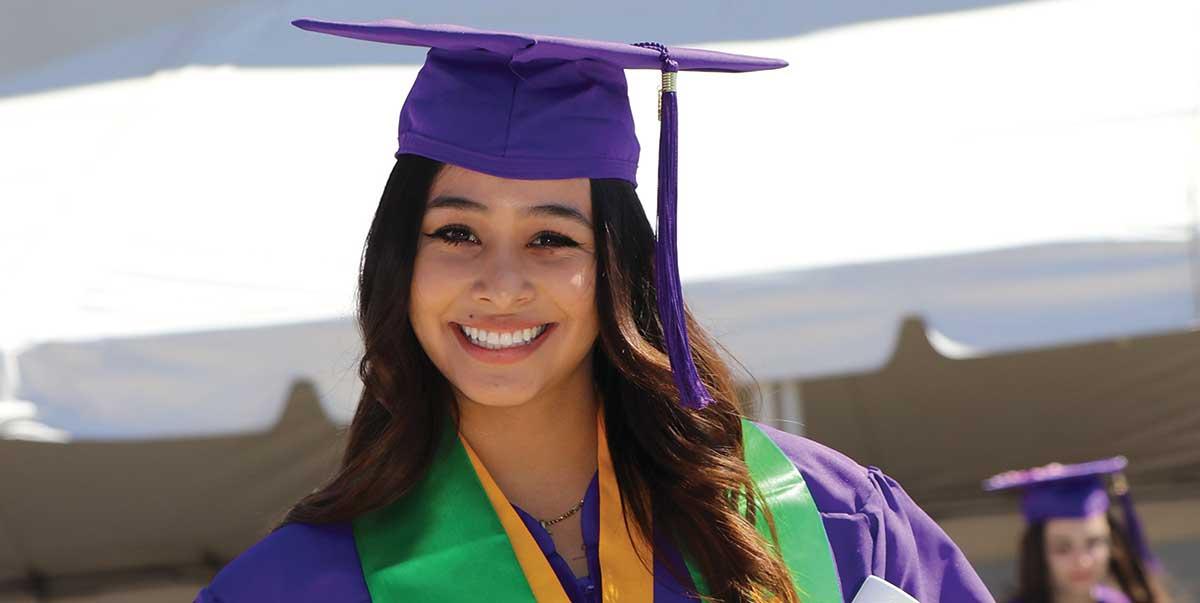 Graduate from San Juan College Standing in cap and gown holding diploma